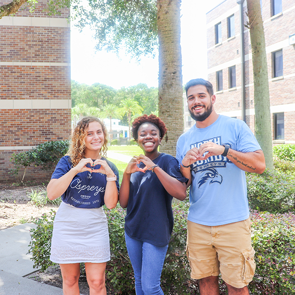 student staff members making hearts with their hands and smiling