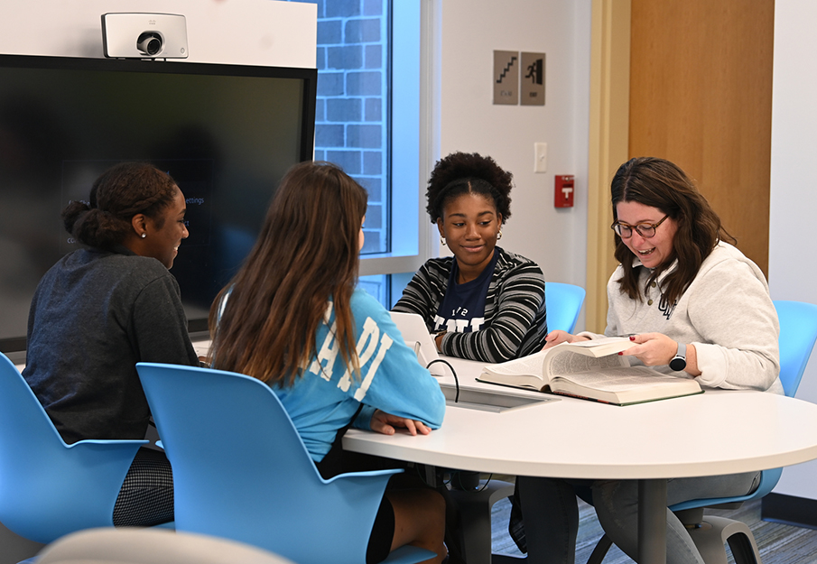 Four students sitting at a table coordinating on a project