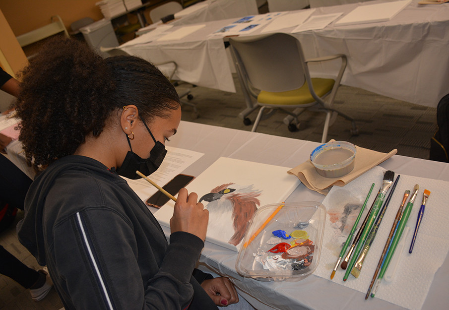 Student painting an osprey on a canvas