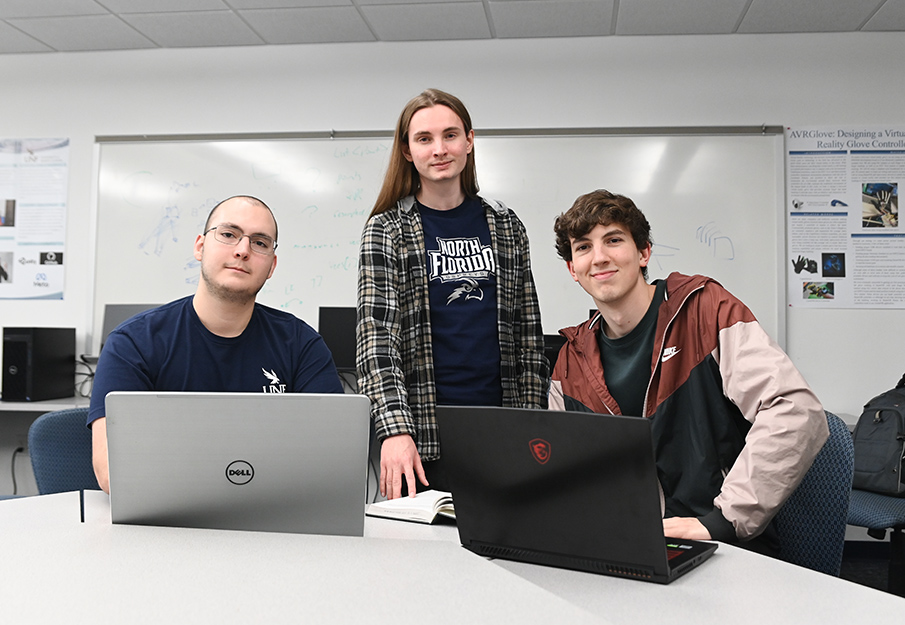 Furio Gerwitz, Troy Kidd and Jake Sutton posed around two open laptops