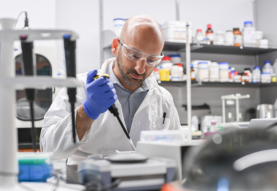 Dr. Bryan Knuckley in a lab putting a sample in a petri dish