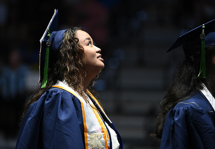 Single student in cap and gown staring upwards