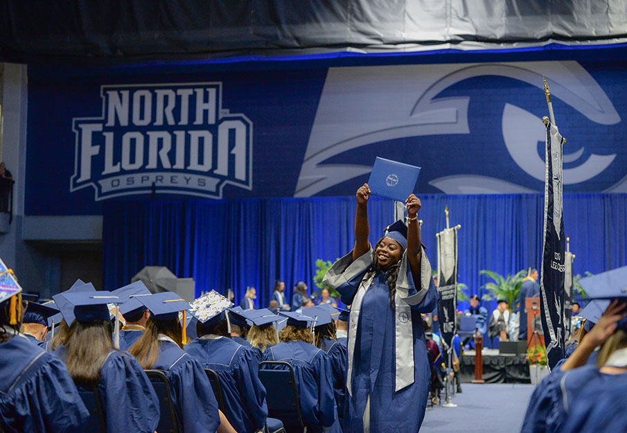 New UNF grad walking down the aisle with her diploma