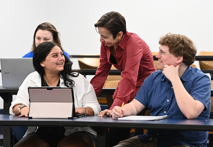 Two business students talking with a professor in a classroom