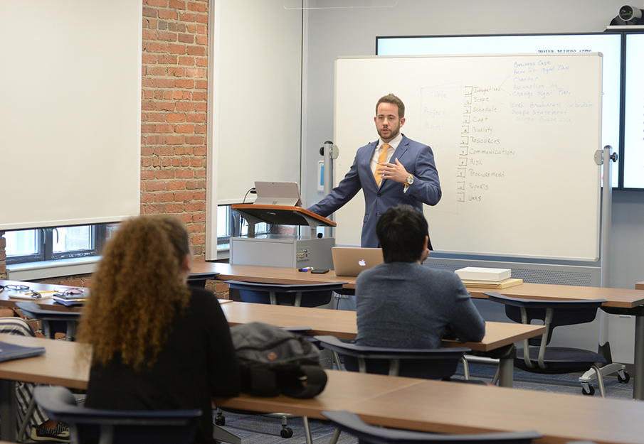 Man in a suite presenting to a small group of executives