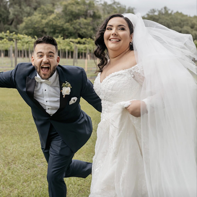 robin and gaby on their wedding day running in a vineyard