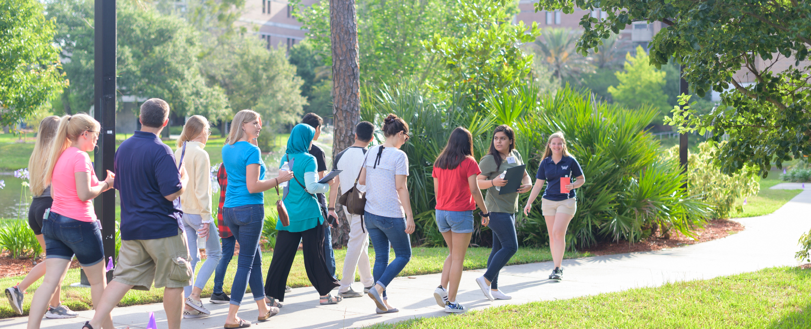 Group on a campus tour following a female tour guide with nice greenery around