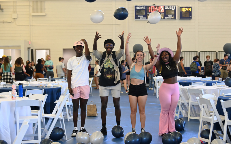 four students throwing balloons in the air