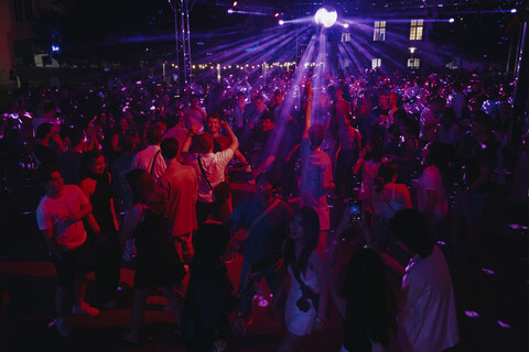 Menschen tanzen bei der Schneckenhofparty. Die Lichtstimmung ist rot-lila.