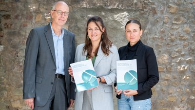  Prof. Dr. Lutz Raphael, Dr. Lena Haase und Alisa Alić mit gedrucktem Zwischenbericht in der Hand