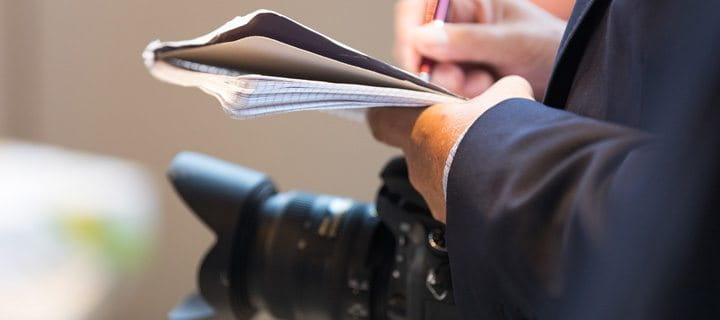 Journalist with camera, pen and paper. 