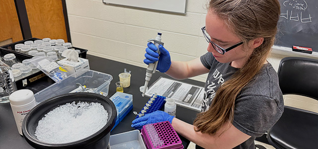 A female student uses a pipette in their science lab