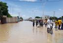 People walk through floodwaters following a dam collapse in Maiduguri, Nigeria (Joshua Olatunji/AP)