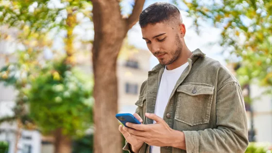 Young boy smiling confident using smartphone at park