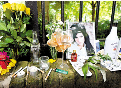 Ta�as de vinho, cigarros e flores colocados por f�s no muro da casa de Amy, em Londres