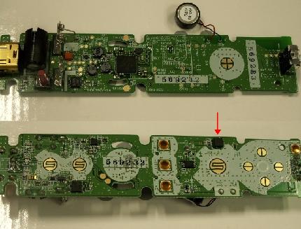 Wiiリモコンの基板。上がリモコンの裏側（電池ボックス側），下が表側（ボタン側）。基板の中央に米Broadcom Corp.のBluetoothチップがある。電池のちょうど裏辺りになる。リモコンの動きを検知する3軸加速度センサは基板のボタン側にあり，Aボタンの横あたりに位置する（赤い矢印）。Wiiリモコン全体の重心より先端よりの場所にある。リモコンの中心軸から位置をずらしているのも意図的だろうか。なお，Wiiリモコンに使われている3軸加速度センサは米Analog Devices, Inc.製だった