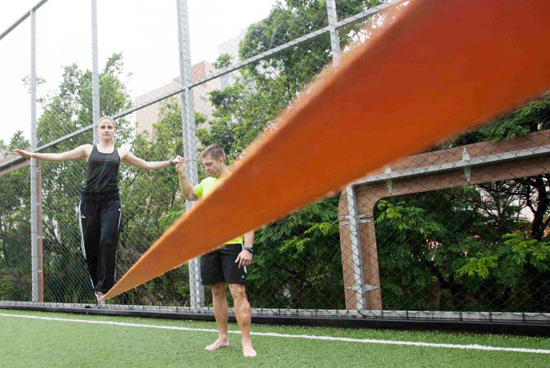 O professor de educa��o f�sica Marcio Trivelato ensinando a estudante Karoline Soria a caminhar na 'slackline', na quadra da academia Competition, em S�o Paulo