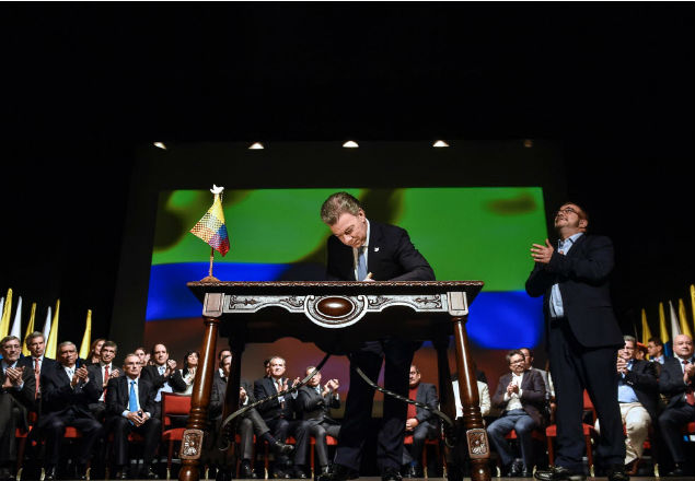 Colombian President Juan Manuel Santos (L) signs the historic peace agreement between the Colombian government and the Revolutionary Armed Forces of Colombia (FARC), at the Colon Theater in Bogota, Colombia, on November 24, 2016. Under pressure for fear that a fragile ceasefire could break down, the government and the Revolutionary Armed Forces of Colombia (FARC) sign the new deal and immediately take it to Congress. The plan bypasses a vote by the Colombian people after they unexpectedly rejected the first version of the deal in a referendum last month. The accord aims to end Latin America's last major armed conflict. But opponents say it is too soft on the leftist FARC force, blamed for many thousands of killings and kidnappings. / AFP PHOTO / Cesar CARRION