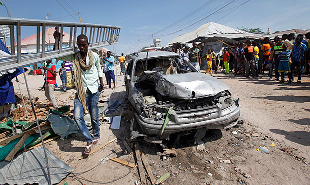 A man walks past a wrecked vehicle after a blast in a market in the capital Mogadishu, Somalia Sunday, Feb. 19, 2017. A Somali police officer says a blast at a busy market in the western part of Somalia's capital tore through shops and food stands and killed more than a dozen people and wounded many others. (AP Photo/Farah Abdi Warsameh) ORG XMIT: NAI104