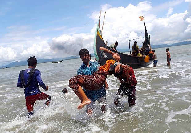 Smoke is seen on Myanmar's side of border as an exhausted Rohingya refugee woman is carried to the shore after crossing the Bangladesh-Myanmar border by boat through the Bay of Bengal, in Shah Porir Dwip, Bangladesh September 11, 2017. REUTERS/Danish Siddiqui TPX IMAGES OF THE DAY ORG XMIT: GGGMUM03