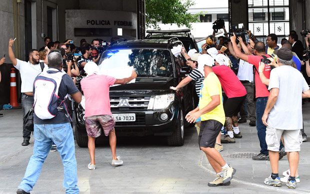 Protesters rush towards the police car that took former governor of Rio Sergio Cabral Filho to the penitentiary Bangu 8, where he will be held on fraud charges, in Rio de Janeiro on November 17, 2016. / AFP PHOTO / TASSO MARCELO ORG XMIT: TAS1151