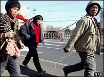 A group of peasants pull a cart filled with their belongings and wood to build a makeshift hut, as they make their way into Beijing 10 January 2003,