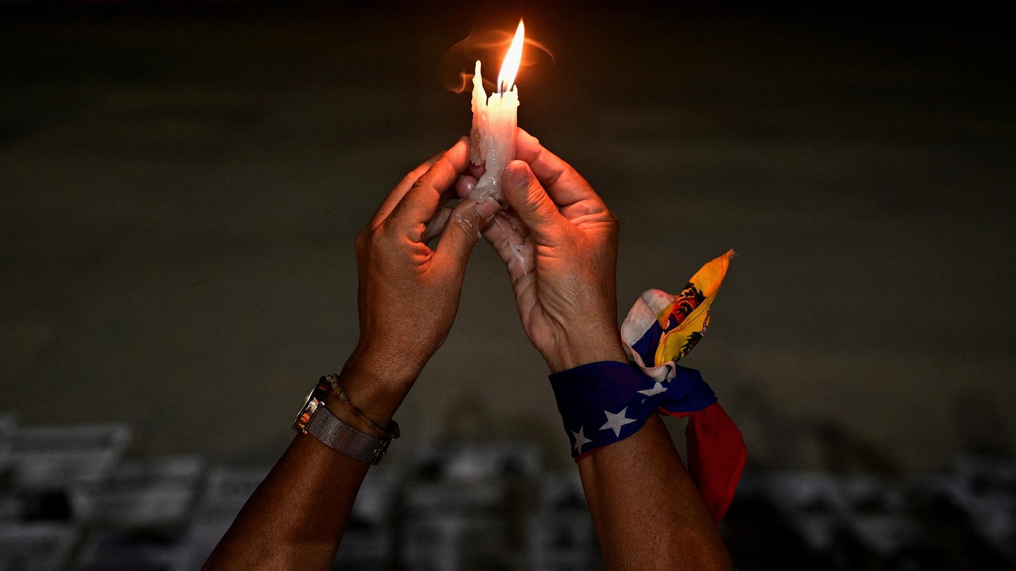 A woman holds a candle at a vigil in honor of Venezuelans detained during protests challenging the presidential election results, Caracas, December 17.