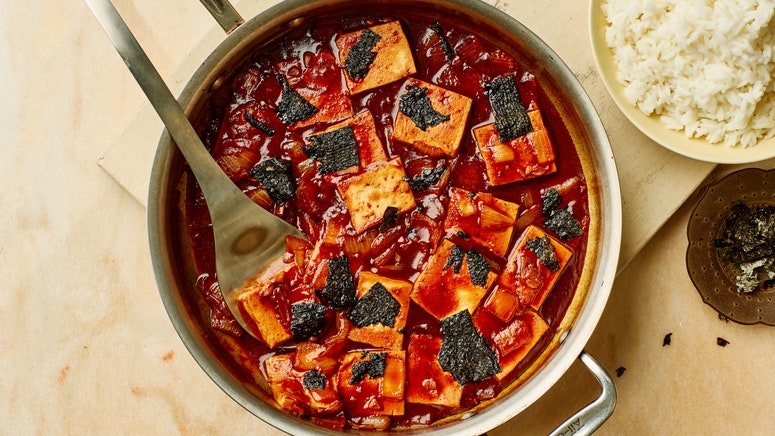 GochujangButterBraised Tofu in a stainless steel pan placed on top of a wooden surface