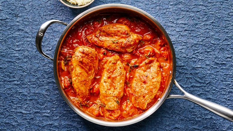 Tomato preserved lemon chicken with herbs in a skillet.