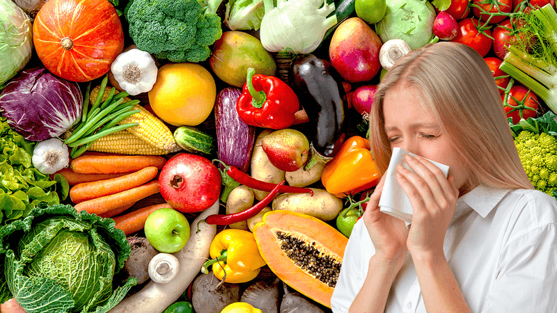 array of different fruits and vegetables overlaid on the right hand side with a blonde woman in a white shirt holding a tissue to her nose and sneezing