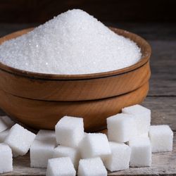 Image of a brown bowl with sugar and sugar cubes next to it. 