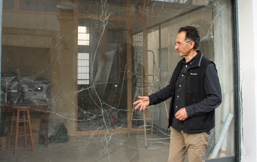 Doros Polykarpou is pictured gesturing towards the window panes of the KISA office in Nicosia — shattered by an explosive device on January 5.
