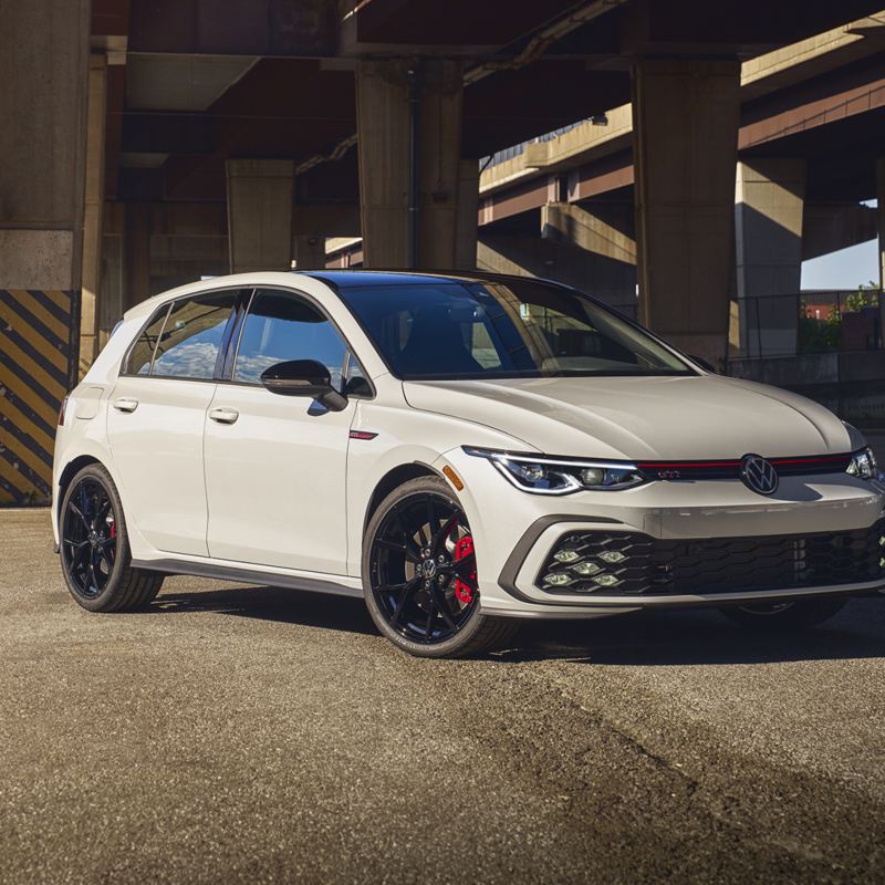 Une Golf GTI 2024 blanche garée sous une autoroute