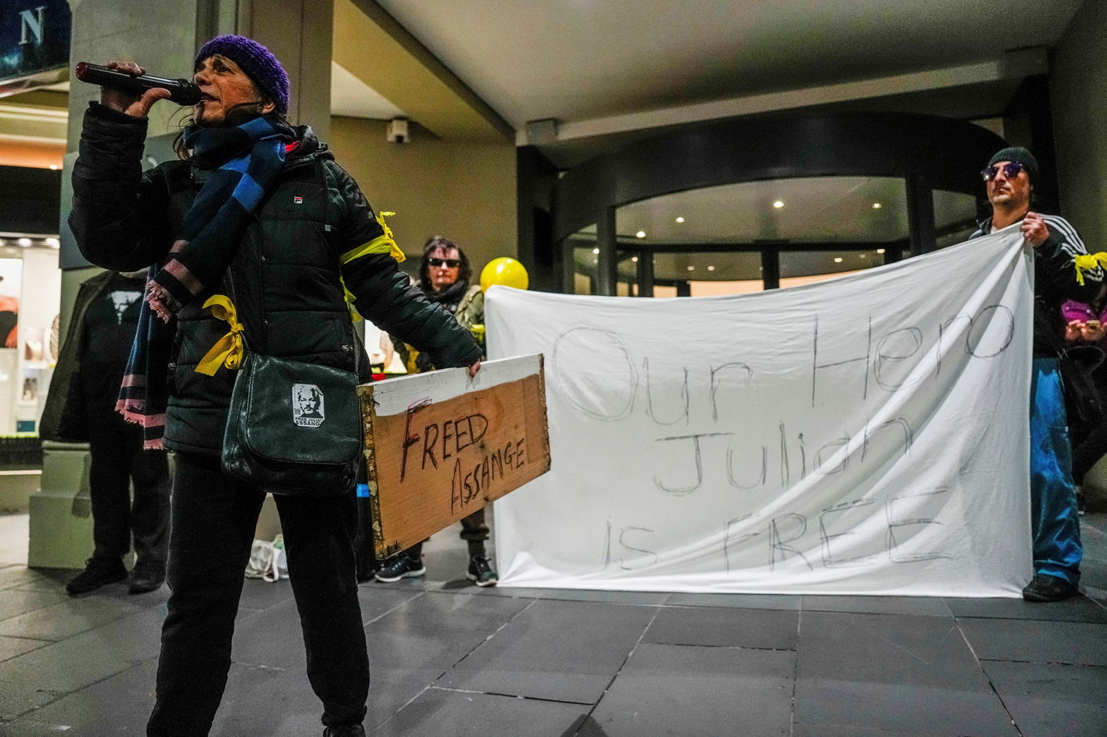 People hold up white sheet saying 'our hero Julian is Free