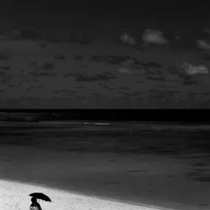 Woman walking beach with black sunshade