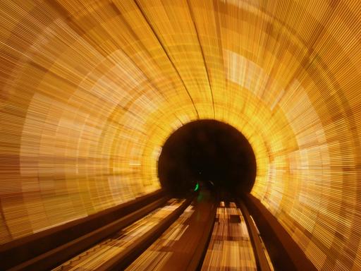 Blick in einen golden ausgeleuchteten Tunnel, der in einem schwarzen Loch endet.