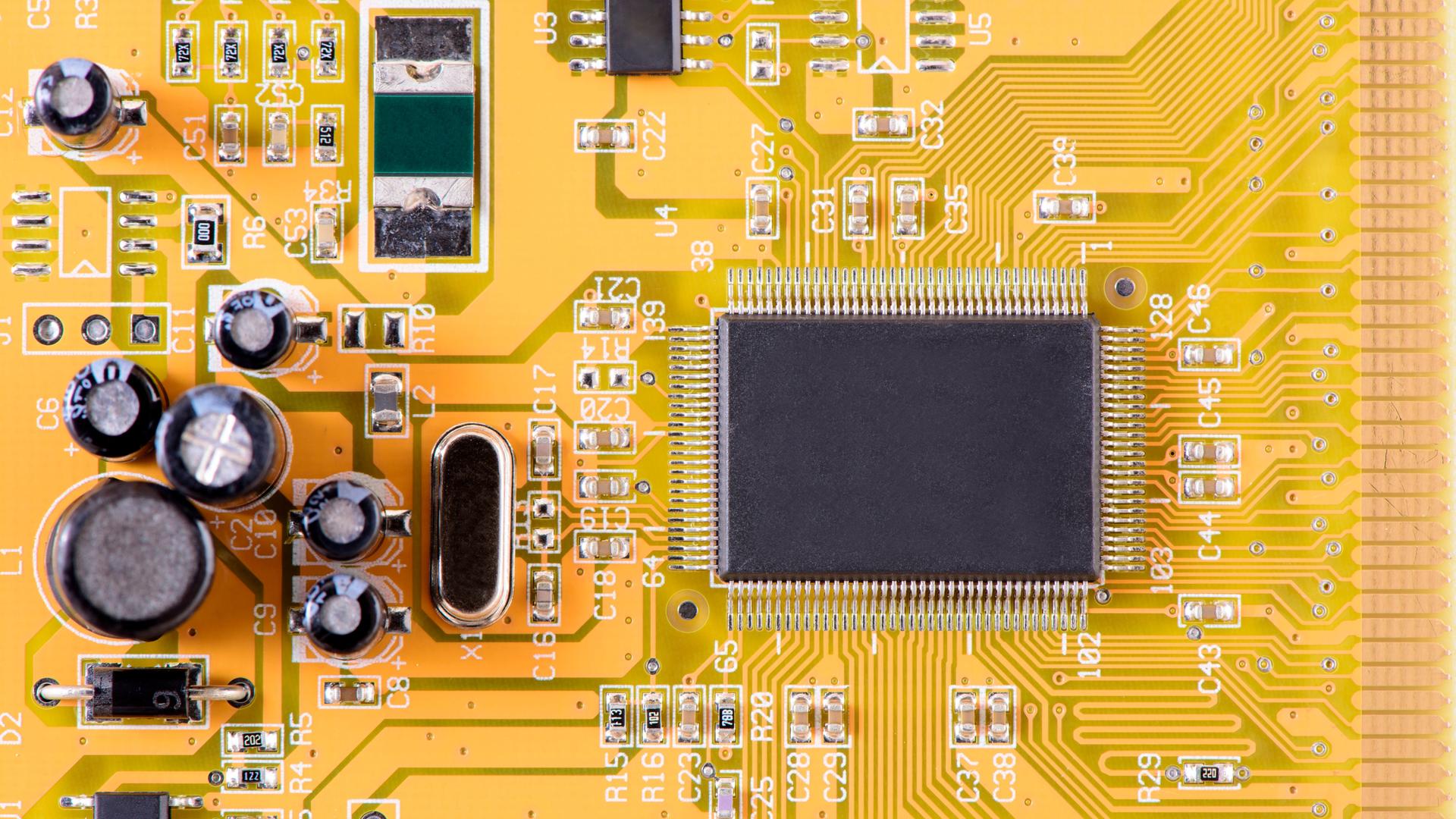 Hauptplatine im Computer mit Leiterbahnen zum Prozessor. Die Platine ist gelb, der Prozessor schwarz.