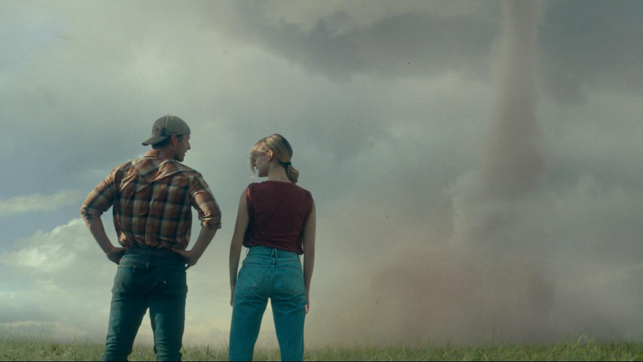 Filmszene aus Twisters zeigt Glen Powell, links, und Daisy Edgar-Jones in der Rückenansicht, wie sie auf einen Tornado schauen.