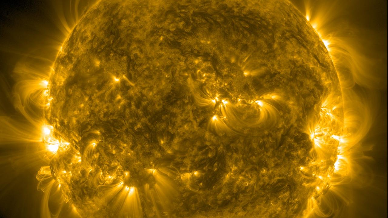 Eine Aufnahme der Sonne, auf Strahlungen und Verwirbelungen kenntlich sind. Es ist ein gelbliche Aufnahme.