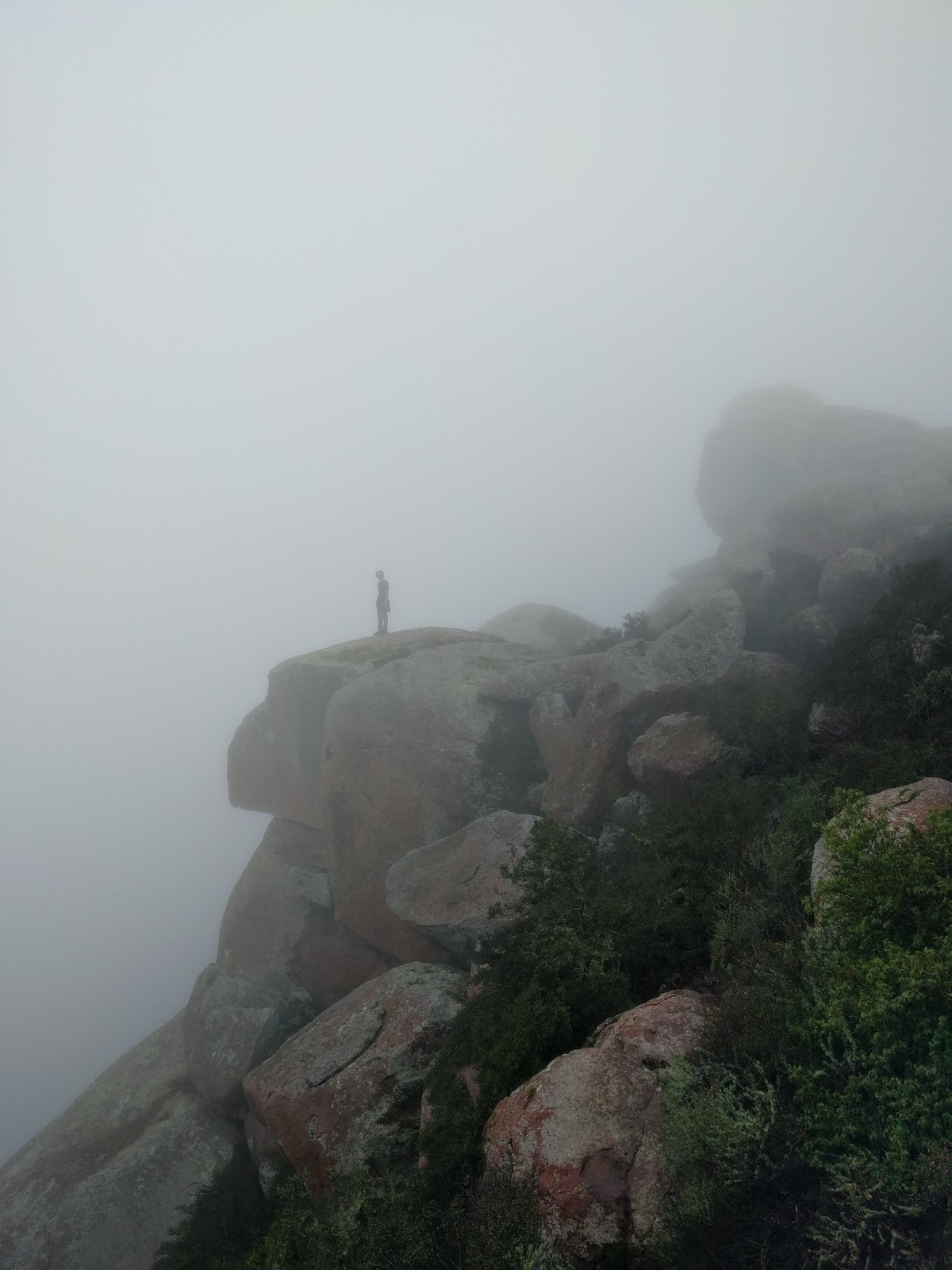 sea, coast, rock, silhouette, person, mountain, fog, mist, morning, hill, peak, foggy, jump, cliff, weather, terrain, mountain top, ridge, summit, climb, motivation, stones, danger, heights, top, risk, metaphor, success, sillhouette, landform, atmospheric phenomenon, mountainous landforms