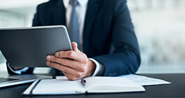 Man in a business suit viewing on tablet at his office desk