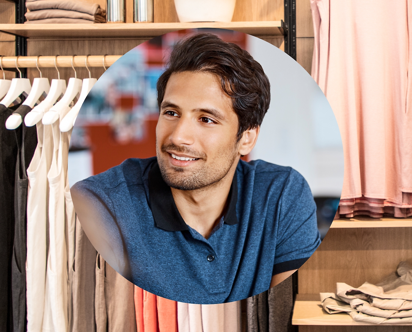 A men smiling with cloths hanging in the background