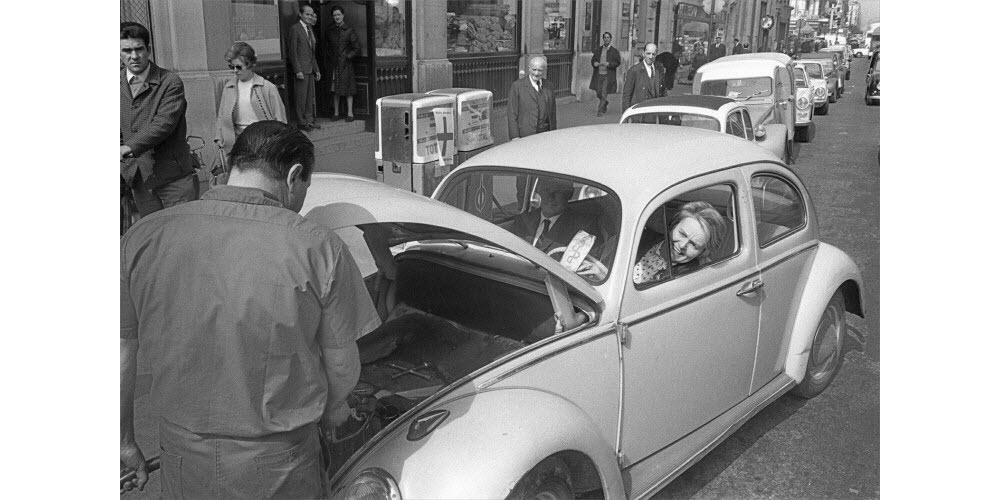 Une femme médecin assise au volant de sa VW se fait ravitailler en essence à Paris. Photo ARCHIVES/AFP