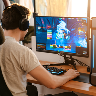 A man wears headphones and plays a game on his PC. 