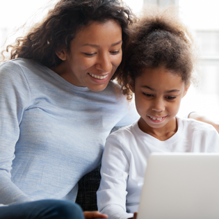 A mom and daughter sit together using a laptop.