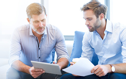 Two men meeting in an office and looking at a tablet