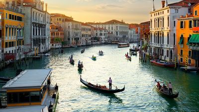 View of the Grand Canal (Canale Grande in Italian) at sunset with gondolas on the water lined by buildings; the main waterway of Venice, Italy