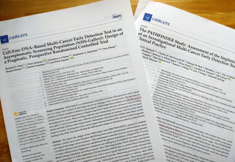 海外で進んでいる、尿や血液などわずかな検体で複数のがんを調べる研究の論文。いずれも検証のために数千人から数万人が参加した研究を実施している＝高野聡撮影
