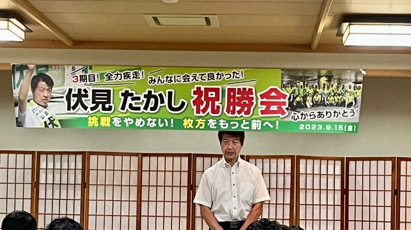 毎日新聞が入手した集会の写真。「祝勝会」「心からありがとう」と書かれた横断幕が掲げられ、大阪府枚方市の伏見隆市長が参加者の前であいさつする姿が写っている＝提供写真