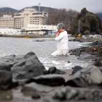 知床観光船事故追悼式に参加後、ウトロ漁港内の海に入って祈る女性＝北海道斜里町で2024年4月23日午後2時51分、貝塚太一撮影